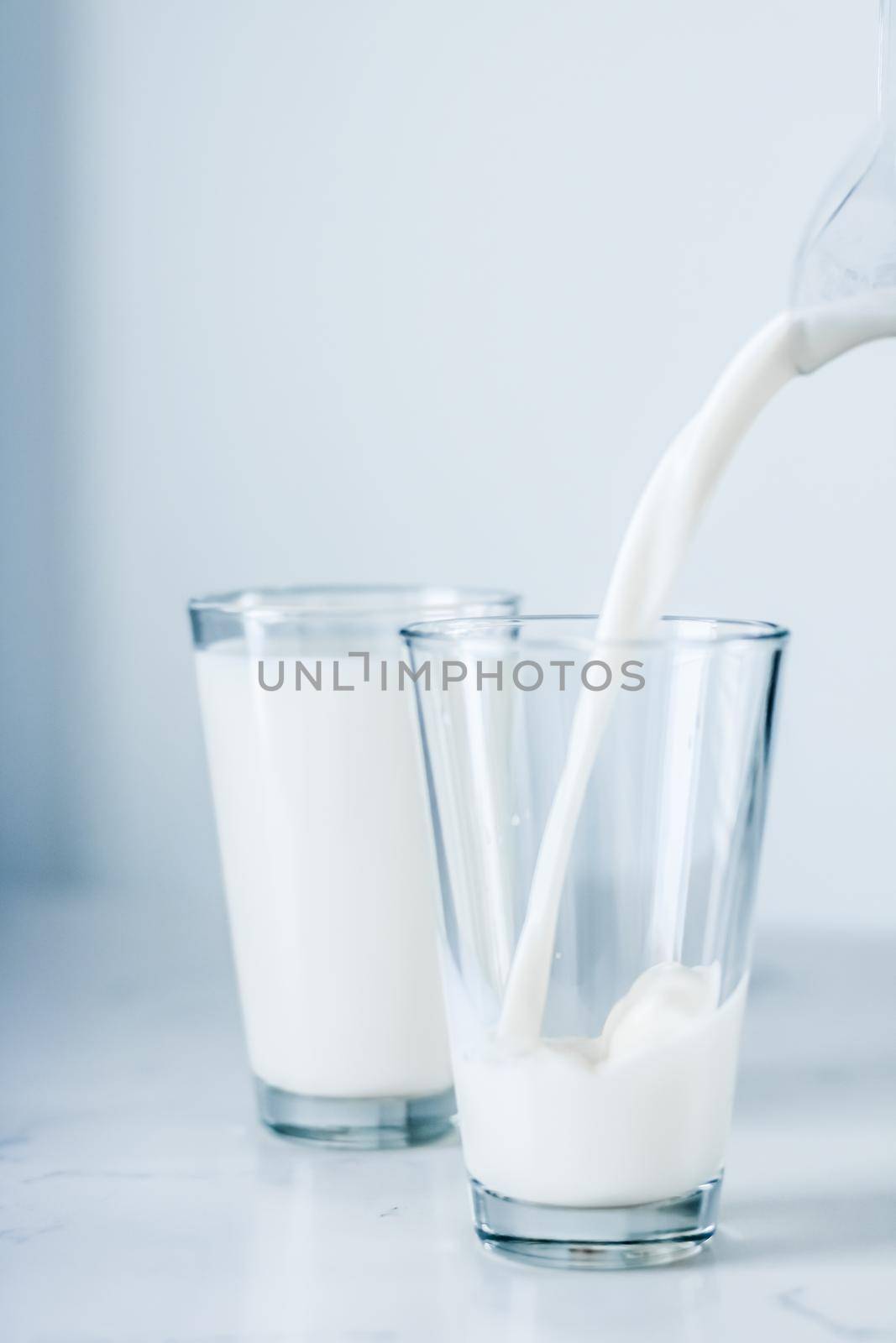 Dairy, healthy nutrition and breakfast concept - World Milk Day, pouring into glass on marble table