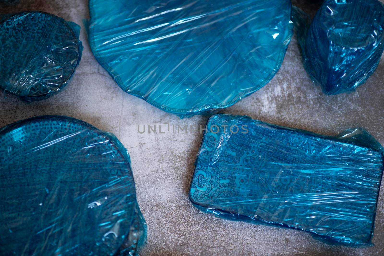 Small plates wrapped in blue cling film placed on brown wooden floor background. Top view. Copy Space. High quality photo