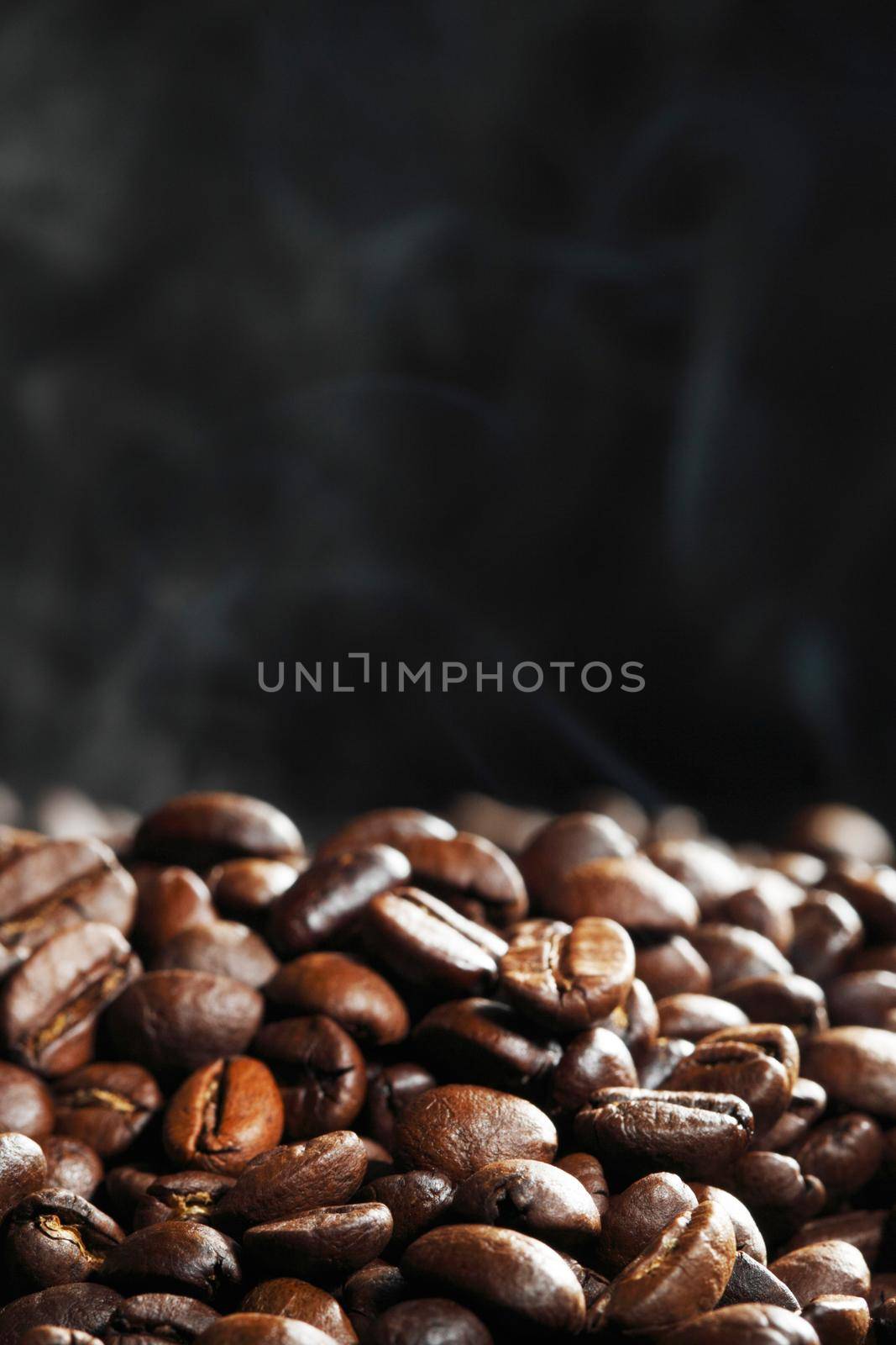 Hot roasted coffee beans and steam on black background with copy space