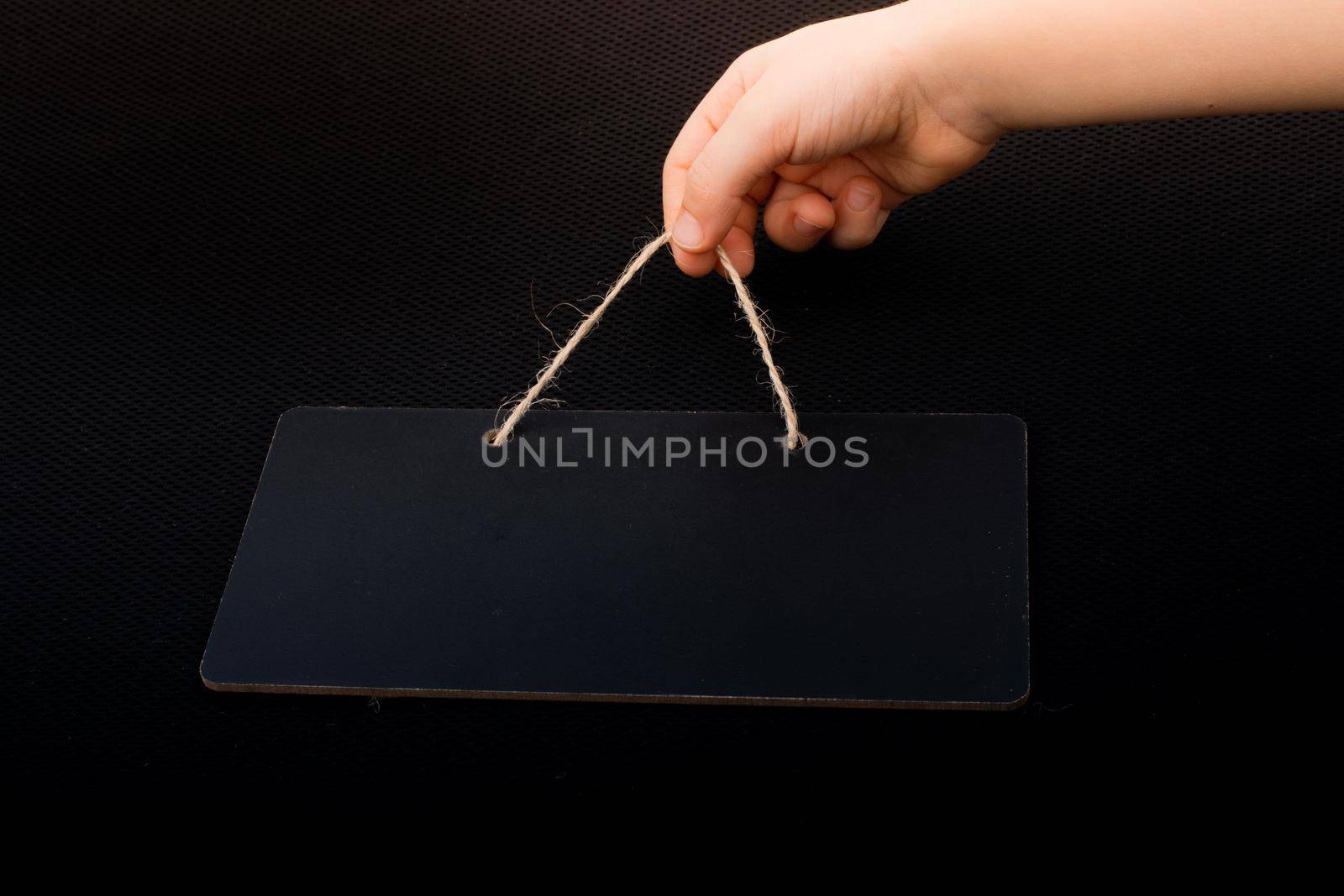 Rectangular shaped black notice board in hand on black background