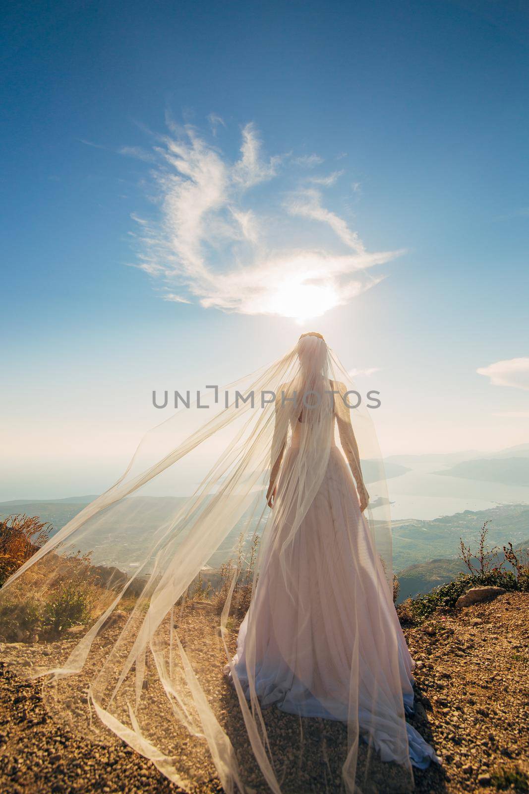 Happy beautiful bride outdoors. Wedding dress fluttering in the wind. Building in the background.