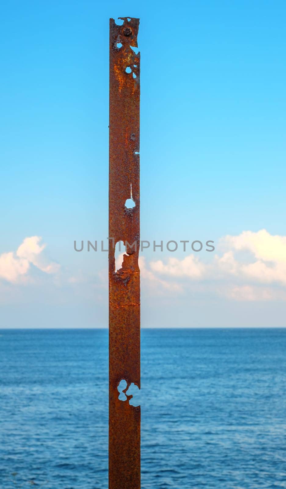 a rusty pipe with the sea behind it