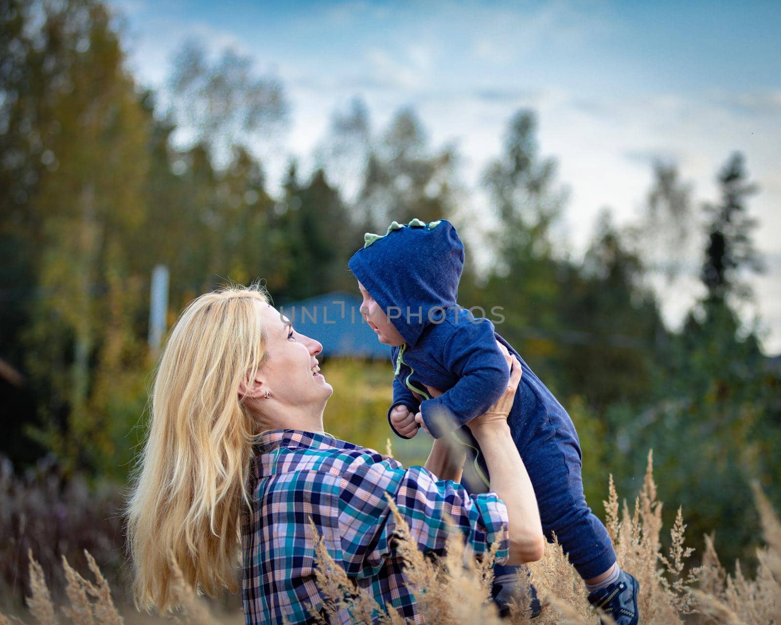 A young mother walks with her baby in a field with tall grass. by Yurich32