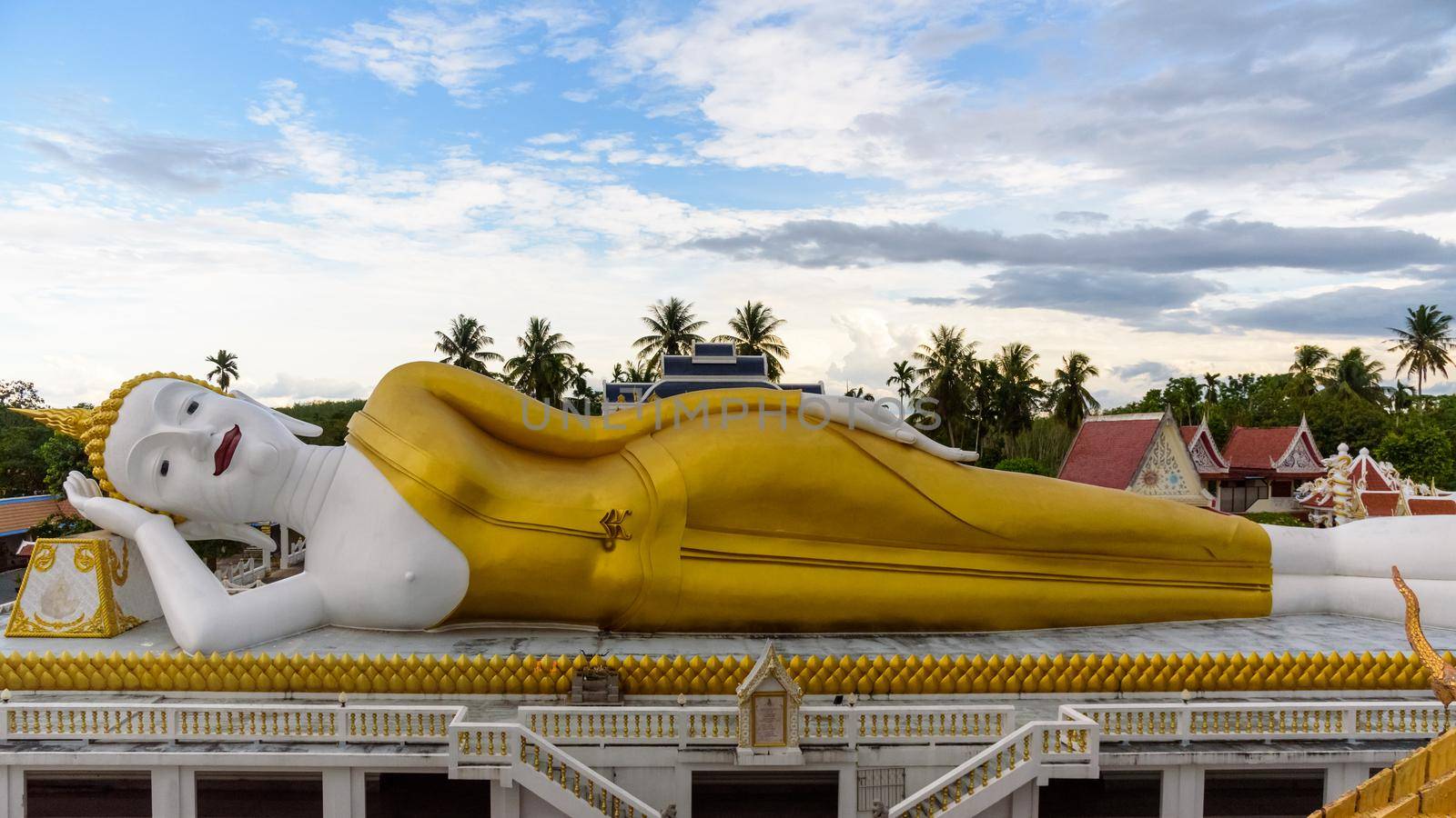 Beautiful white and gold Buddha statues in the reclining position under the blue sky in the evening at Wat That Noi, It is Buddhist temple are landmark of Nakhon Si Thammarat province, Thailand