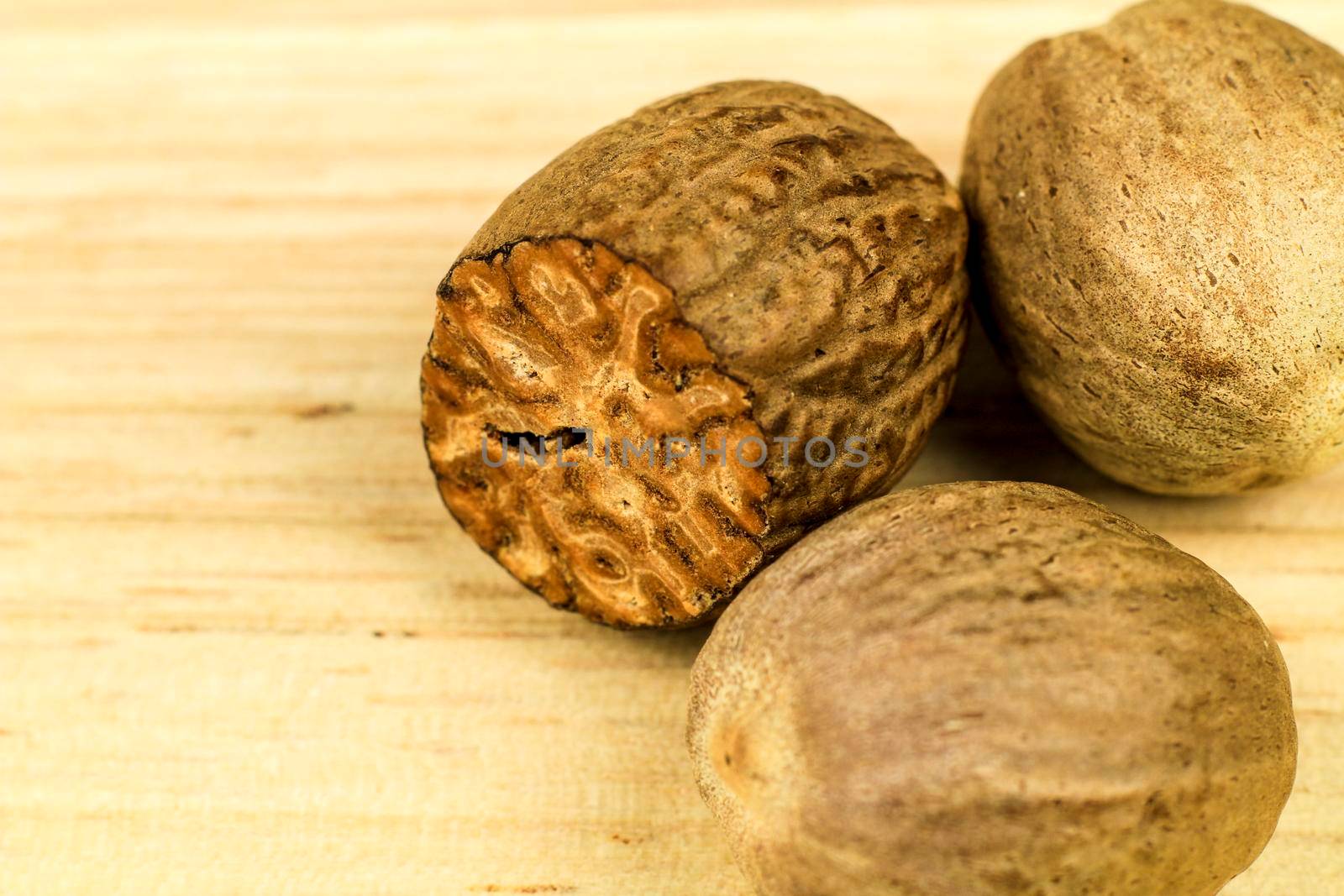 Natural and tasty Nutmegs on brown wooden board