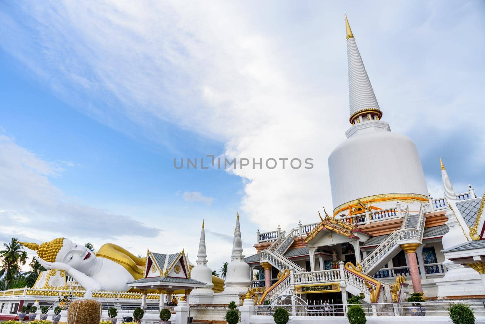 Large white pagoda and Buddha statue under the blue sky in the evening at Wat That Noi, It is Buddhist temple are landmark of Nakhon Si Thammarat province, Thailand