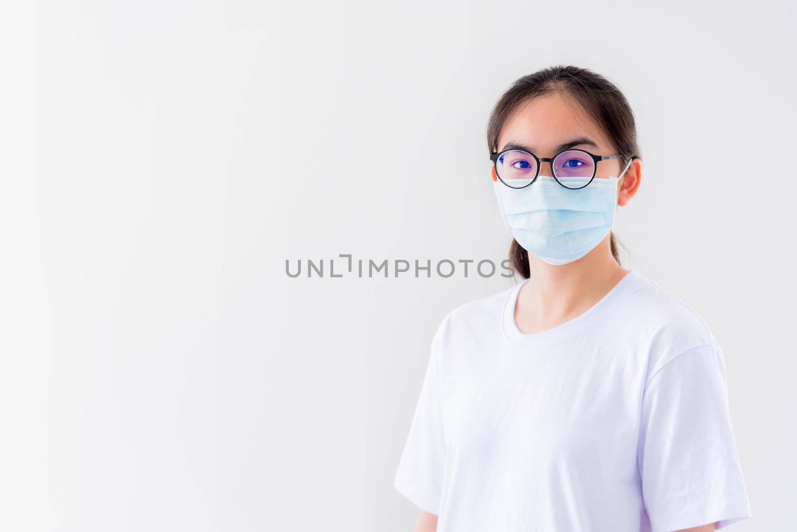 Studio portrait Asian young woman wears glasses and mask to protect against Coronavirus looking at camera, Thailand girl people on white background blank or copy space for anti virus Covid 19 concept