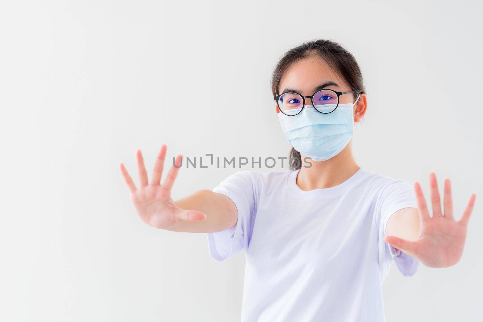 Portrait Asian young woman wears glasses and mask to protect against Coronavirus looking at camera, girl show hands stop coronavirus outbreak isolated on white background stop virus Covid 19 concept