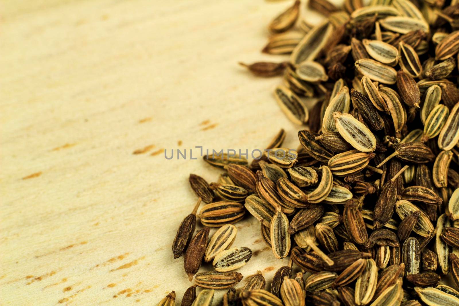 Organic dried fennel seeds on brown wooden board