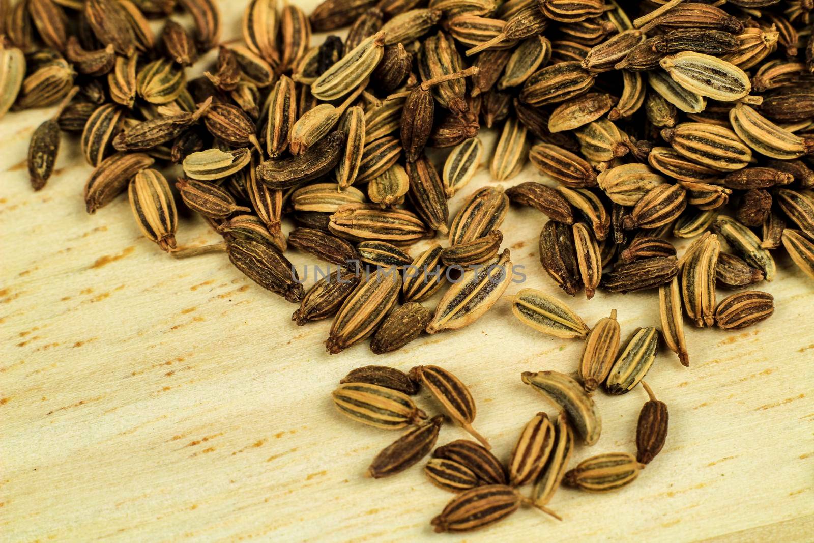 Organic dried fennel seeds on brown wooden board