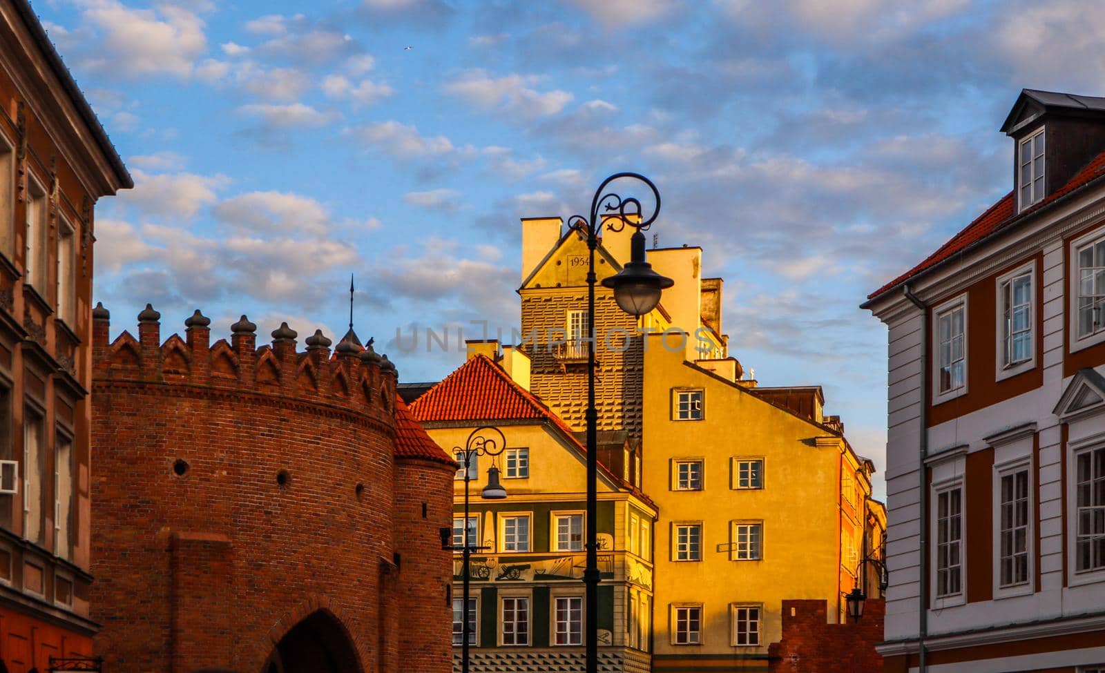 Historic buildings and red brick walls of Warsaw Barbican Poland at sunset in spring by Olayola