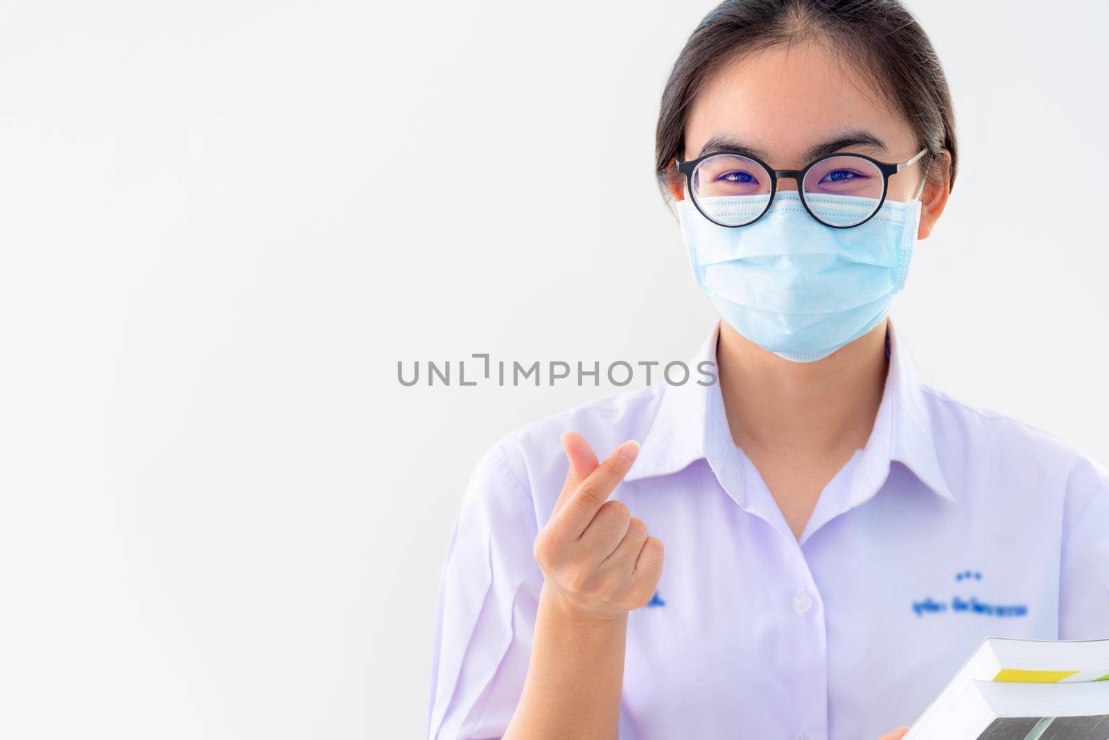 Student Asian young woman wear a mask to protect Coronavirus, Girl to encourage show two fingers mini heart symbol love to fight and strong on white background health care from Covid 19 virus outbreak