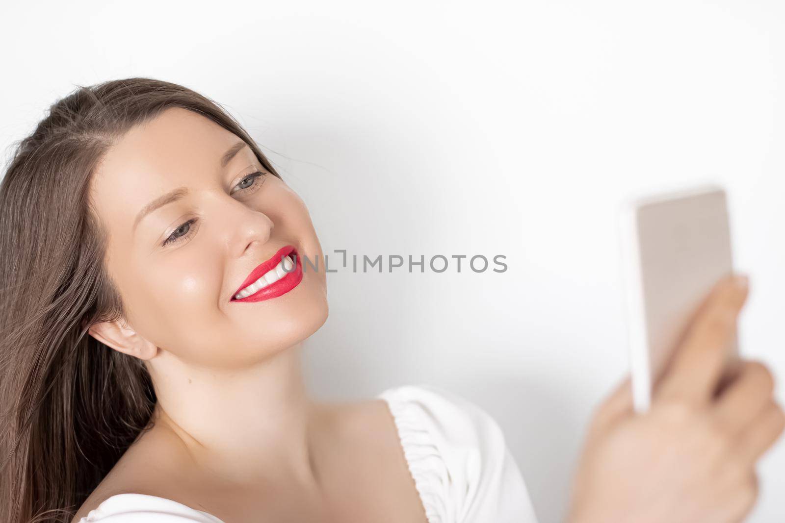 Happy smiling woman with smartphone having video call or taking selfie, portrait on white background. People, technology and communication concept by Anneleven