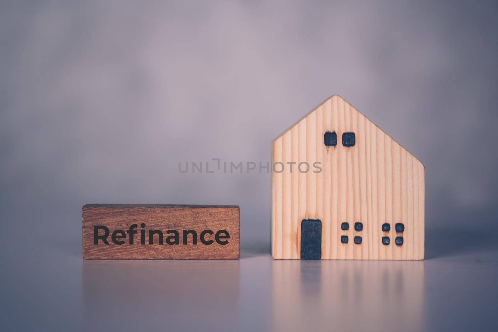 Wooden block with refinance word and house model about home and finance, loan and mortgage for real estate and property, residential and planning with budget, investment and earning, business concept.