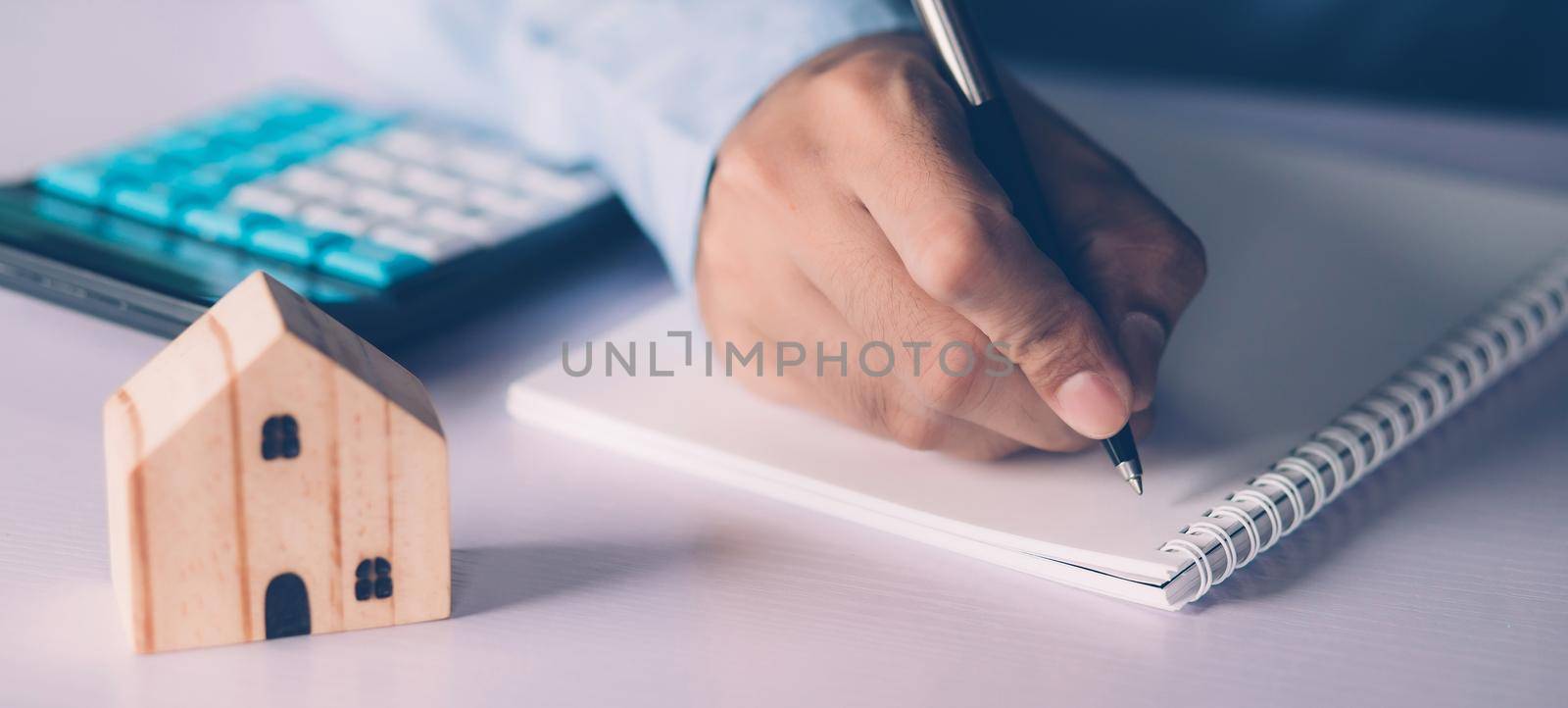 Hand of businessman planning and writing on note expense and mortgage with home, insurance house, finance and investment, calculate loan of residential, cost for refinance of property concept.