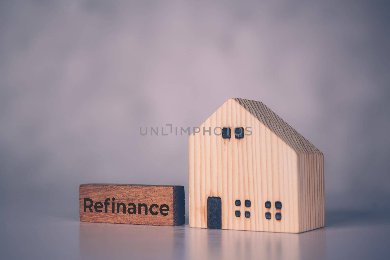 Wooden block with refinance word and house model about home and finance, loan and mortgage for real estate and property, residential and planning with budget, investment and earning, business concept.