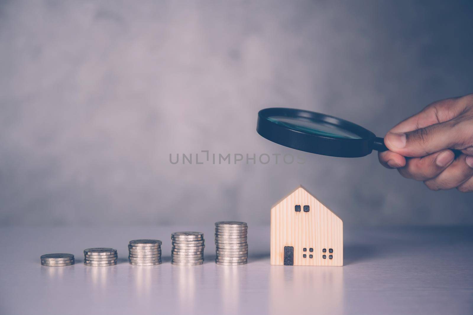 Hands of businessman holding magnifying glass home model with search real estate and property investment for profit, planning of residential and income, loan and mortgage, business concept. by nnudoo