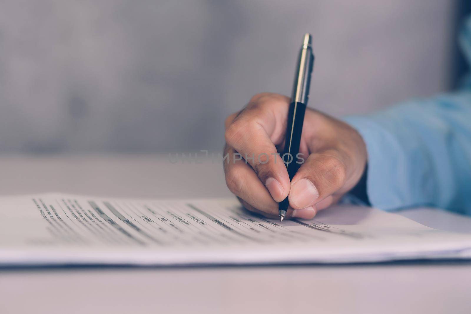 Hands of businessman signing contract about agreement for success on desk in the office, man signature document paperwork with pen, legal insurance and decision for deal, business concept. by nnudoo