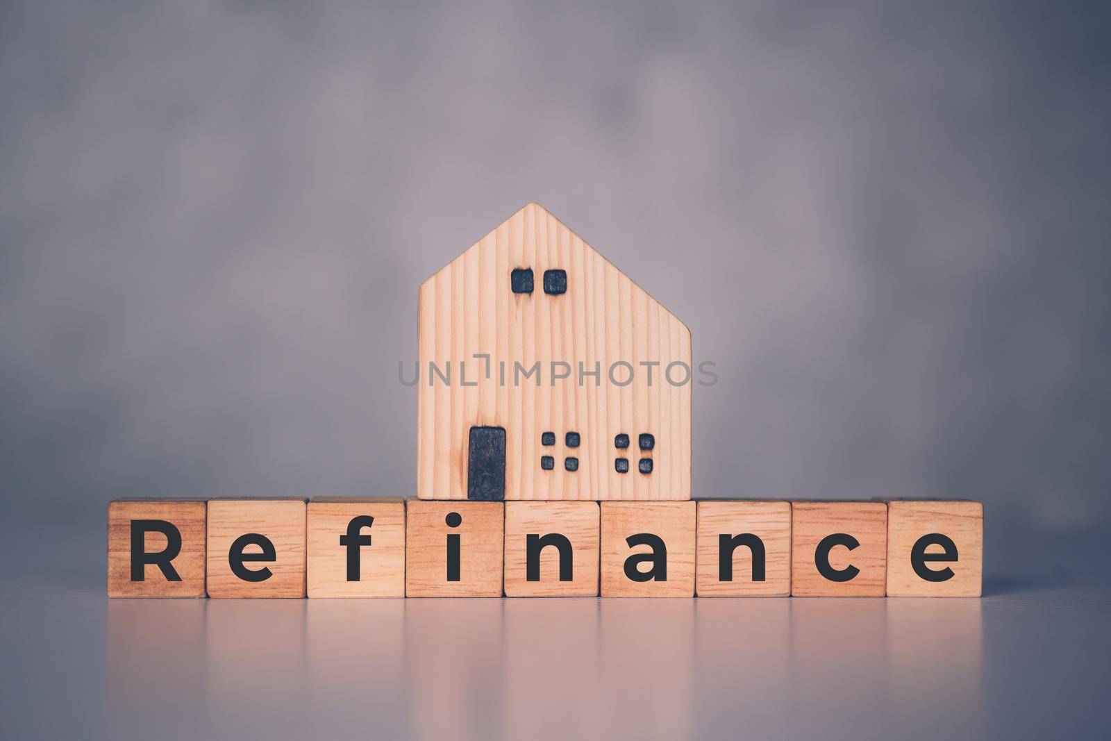 Wooden block with refinance word and house model about home and finance, loan and mortgage for real estate and property, residential and planning with budget, investment and earning, business concept.