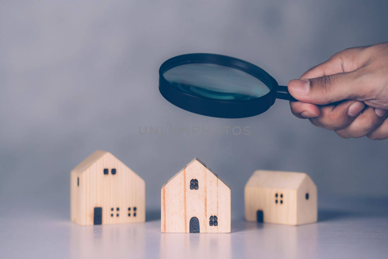 Hand of businessman hold magnifying glass looking house for examining and analyzing quality, inspection and choice home, purchase and search residential and investment, business and property concept.