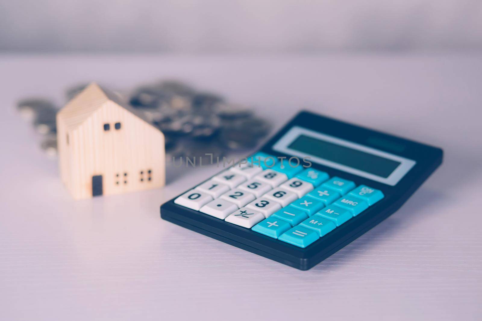 Investment about home with calculator and model house and coins on desk, property and real estate and mortgage, loan and finance, financial saving and account for residential, business concept.