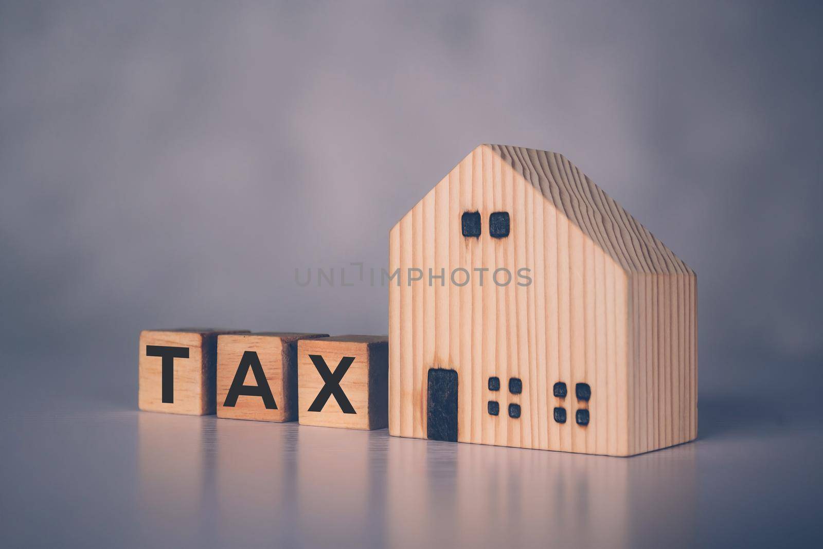 Wooden block cube with TAX word and home model, real estate and property about finance, planning with financial, investment about residential and tax, budget and taxation, business concept.