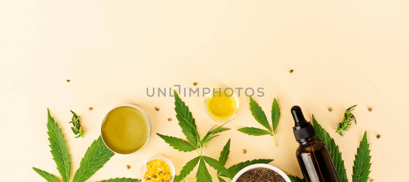 Alternative medicine, natural cosmetics. cbd oil and cannabis leaves cosmetics top view on orange background, flat lay