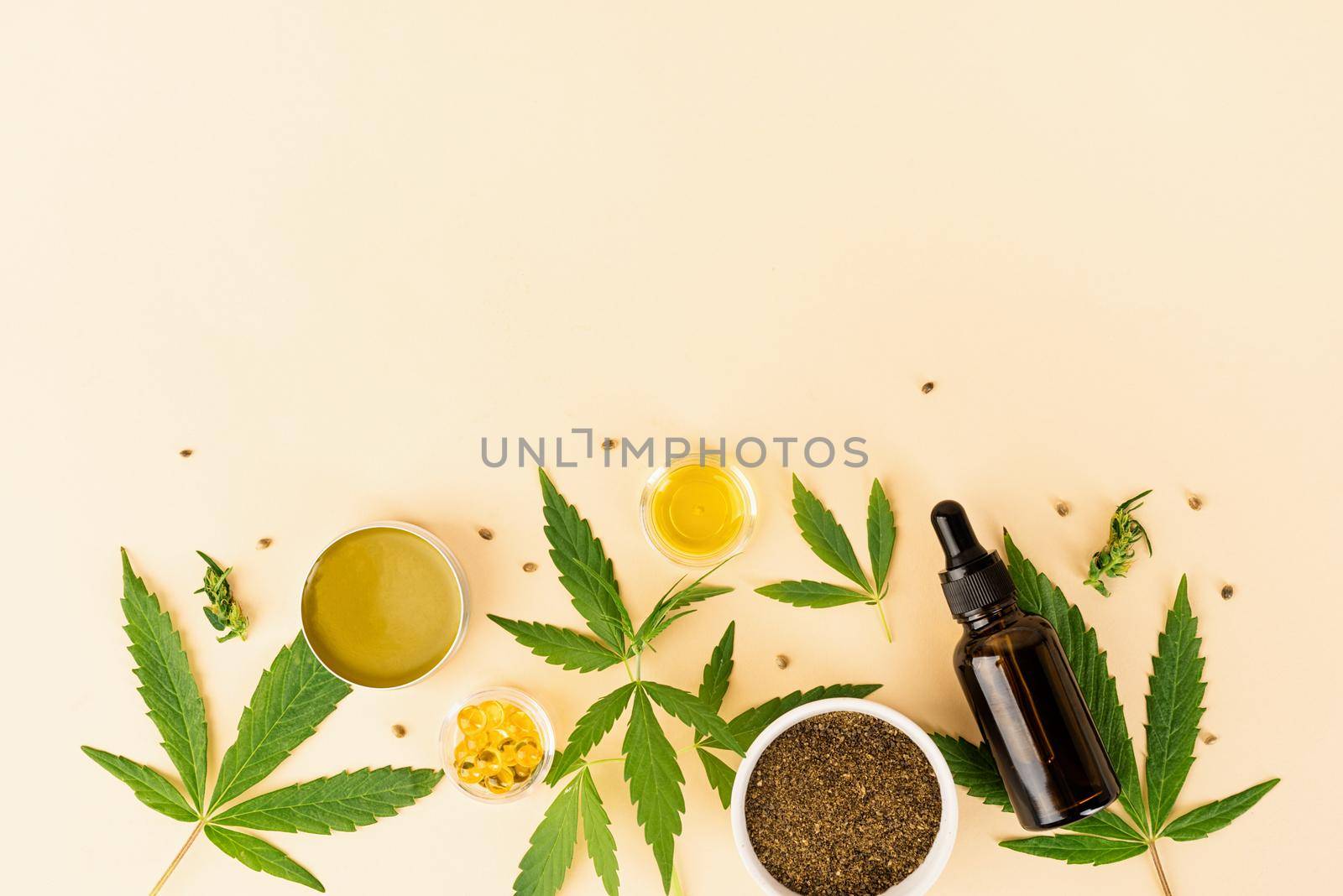 Alternative medicine, natural cosmetics. cbd oil and cannabis leaves cosmetics top view on orange background, flat lay