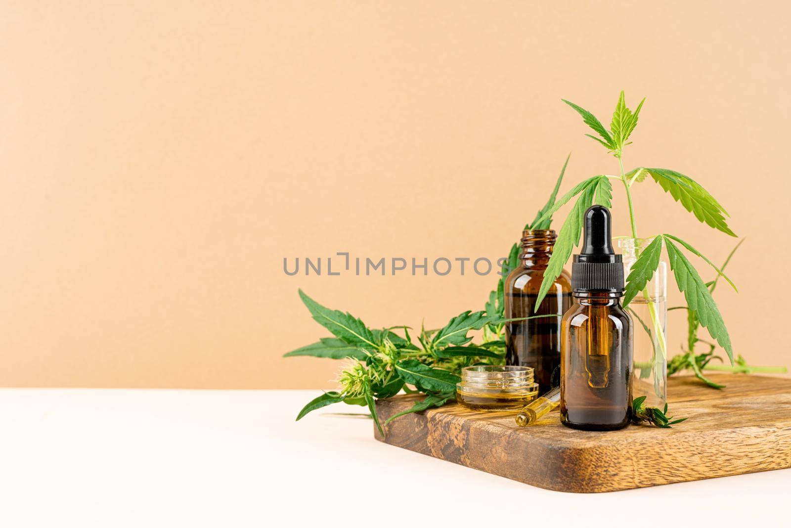 Alternative medicine, natural cosmetics. cbd oil and cannabis leaves cosmetics front view on orange background, copy space