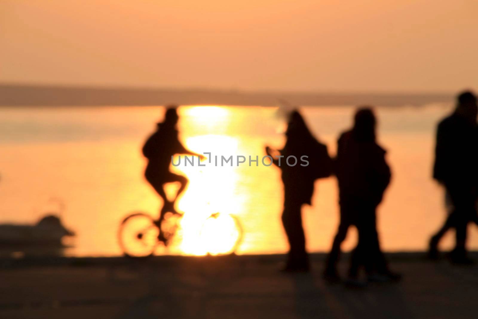 People relaxing and riding bikes at sunset on the banks of the Douro River in Oporto, Portugal.