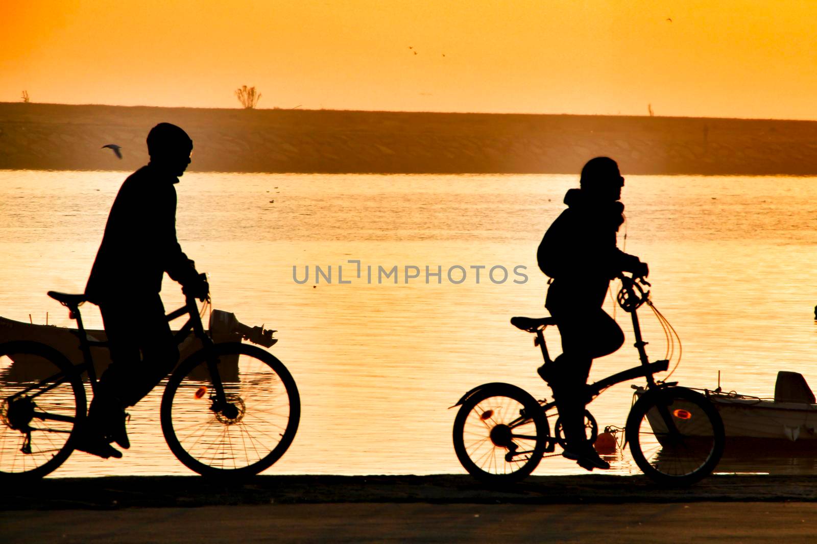 People relaxing and riding bikes at sunset on the banks of the Douro River in Oporto, Portugal.