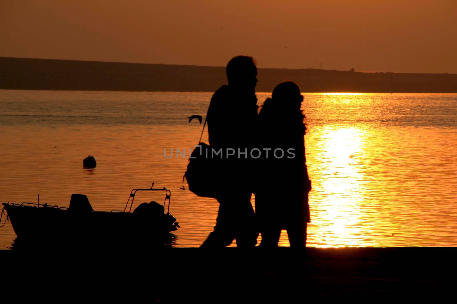 People relaxing and walking at sunset along the banks of the Douro River in Oporto, Portugal.