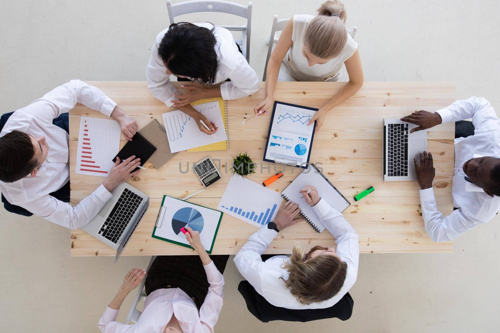 Business people at meeting working together with laptop, business summary charts, contract and insurance documents at wooden table in office. Teamwork concept.