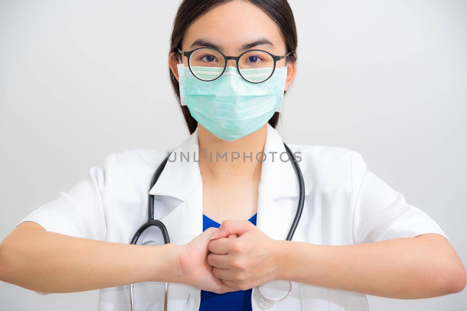 Portrait beautiful Asian woman doctor with stethoscope and mask to protect Corona Virus clasp hand gesture of beg for help cooperation, work together confederate to stop the epidemic COVID 19 concept