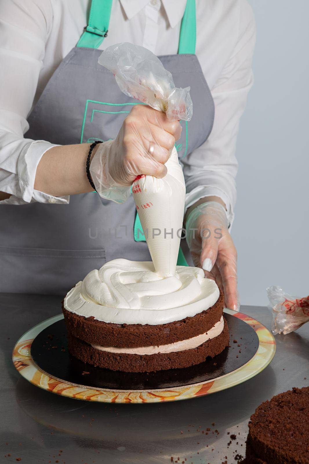 Woman hands chef spreading cream on second layer of Chocolate cake. Making Chocolate Layer Cake. Series.