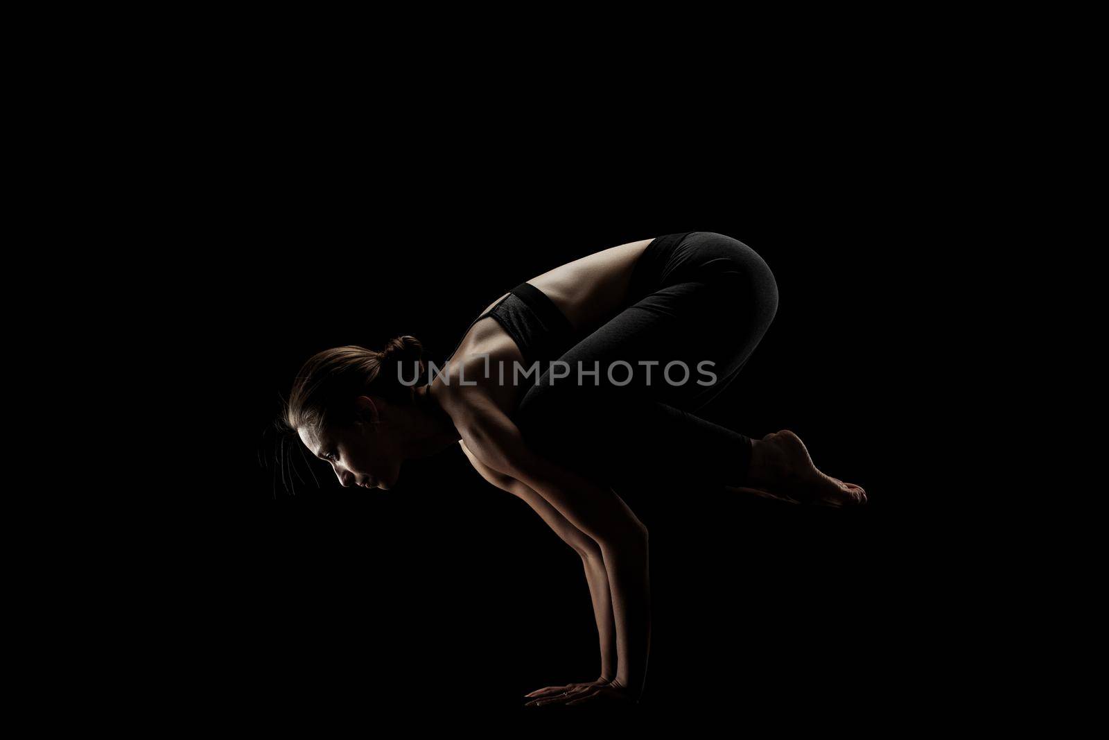 cute caucasian girl exercising yoga poses against dark backgroung. side lit silhouette. by kokimk