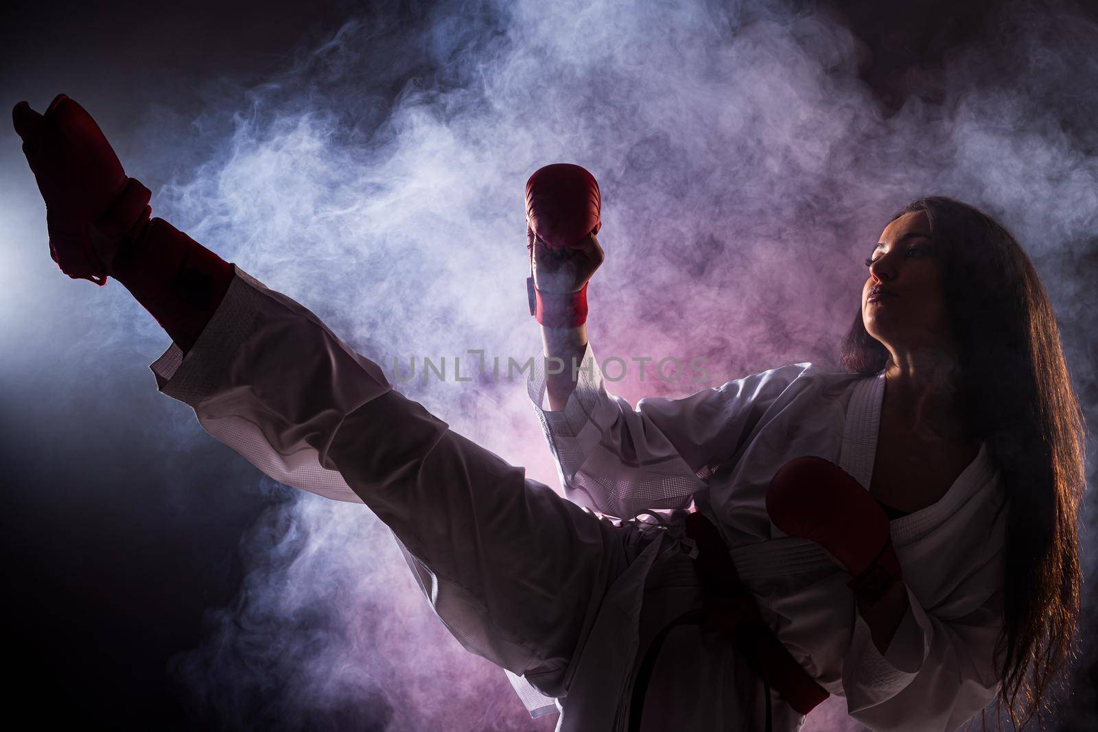 girl exercising karate leg kick against red fog background