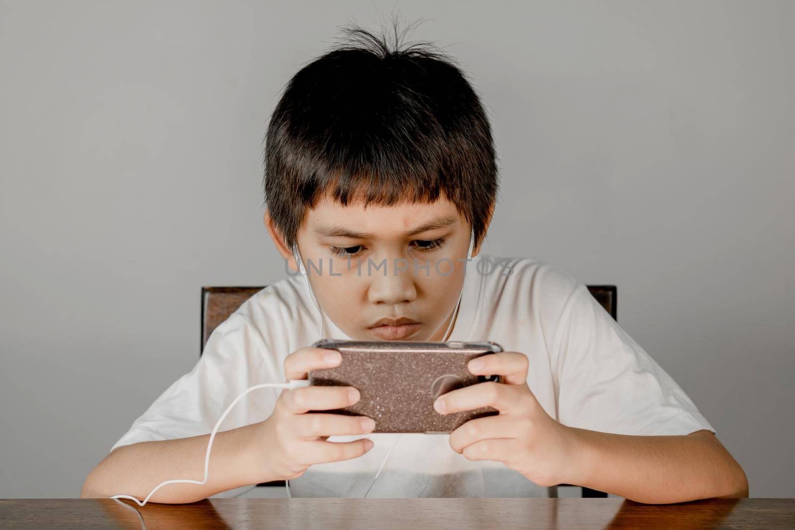 Closeup of a boy's face wearing headphones and intending to play games on his smartphone.