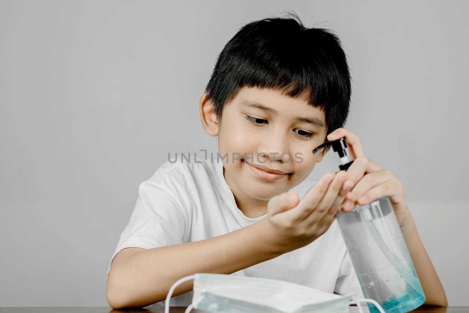 Closeup of a boy face washing his hands with alcohol gel.