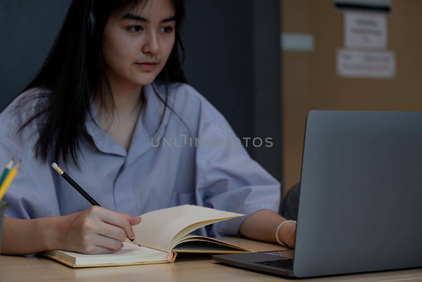 Close up hand of asian student taking note during online lesson with laptop, Study Education at home. by nateemee