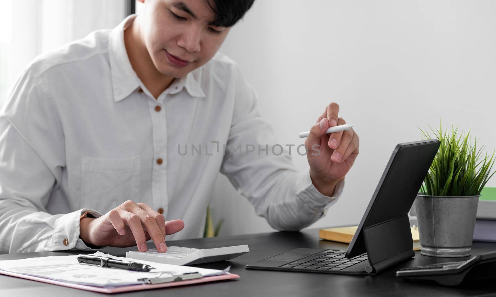 man accountant working with digital tablet computer and calculator for business and financial expense at home office.