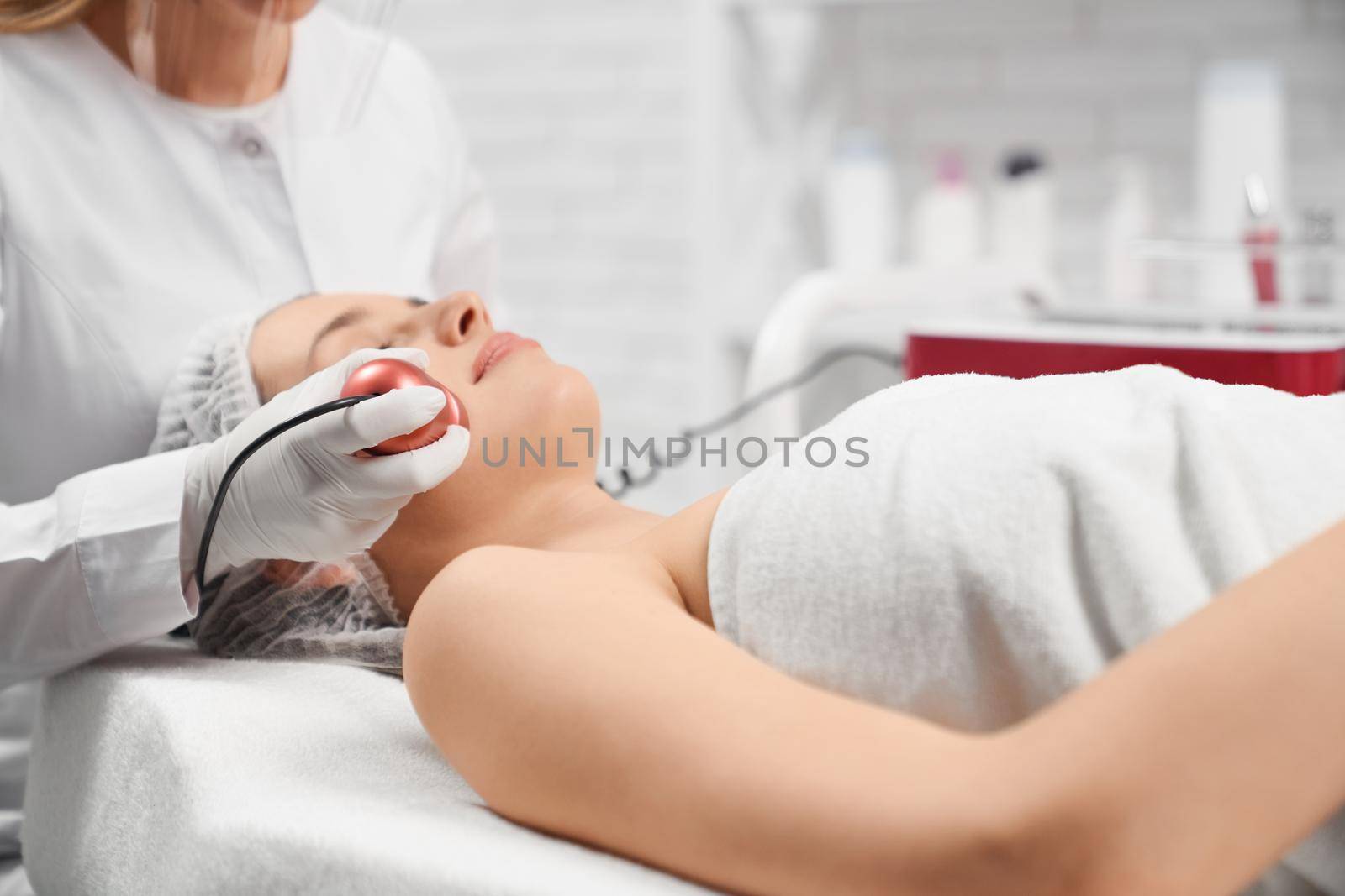 Side view of young beautiful woman lying on procedure for face in beautician. Concept of special beauty procedure anti-aging and improvements skin with cosmetics.