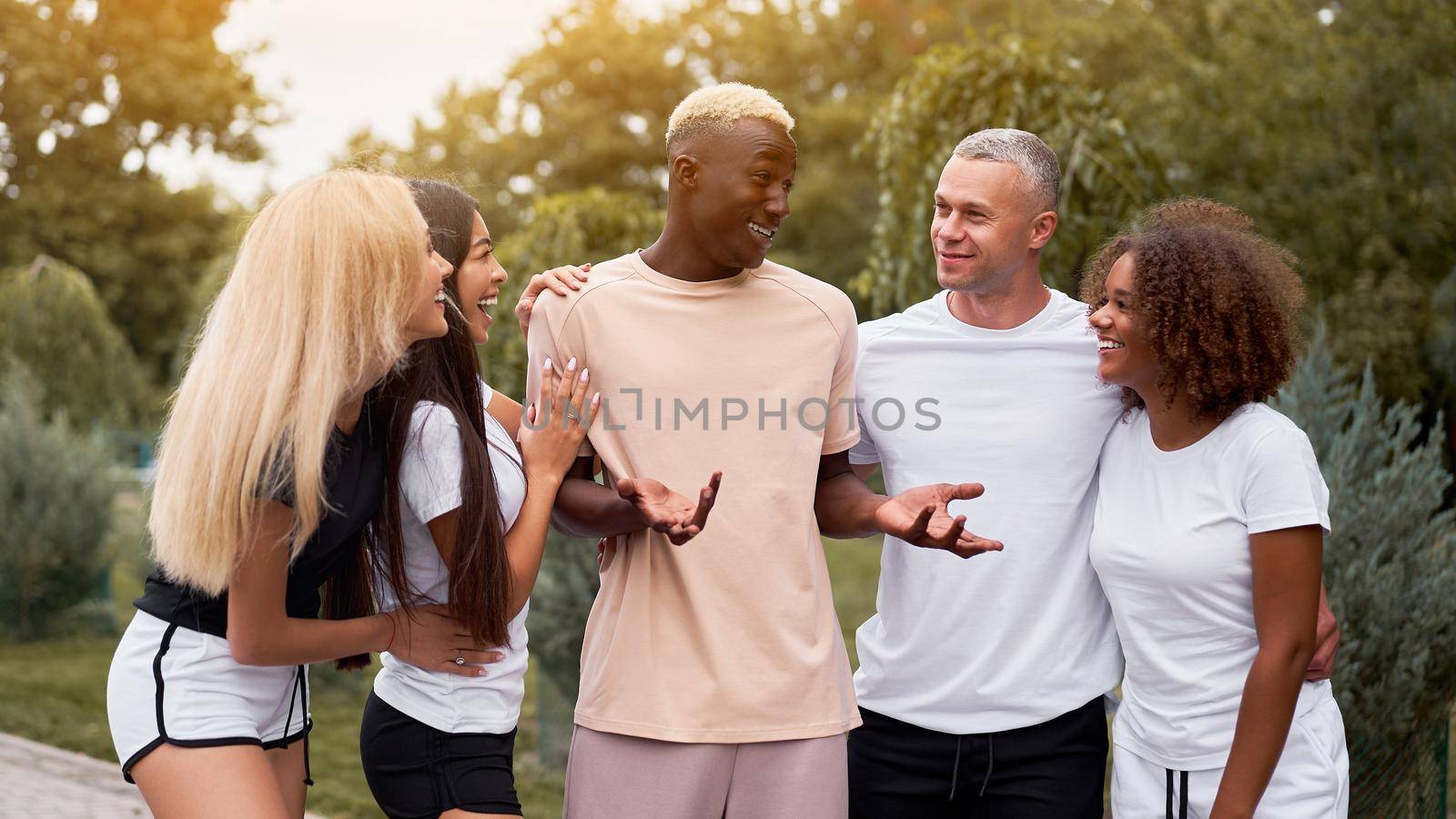 Multi-ethnic group teenage friends. African-american asian caucasian student spending time together Multiracial friendship Happy smiling People dressed black white sportswear meeting outdoor