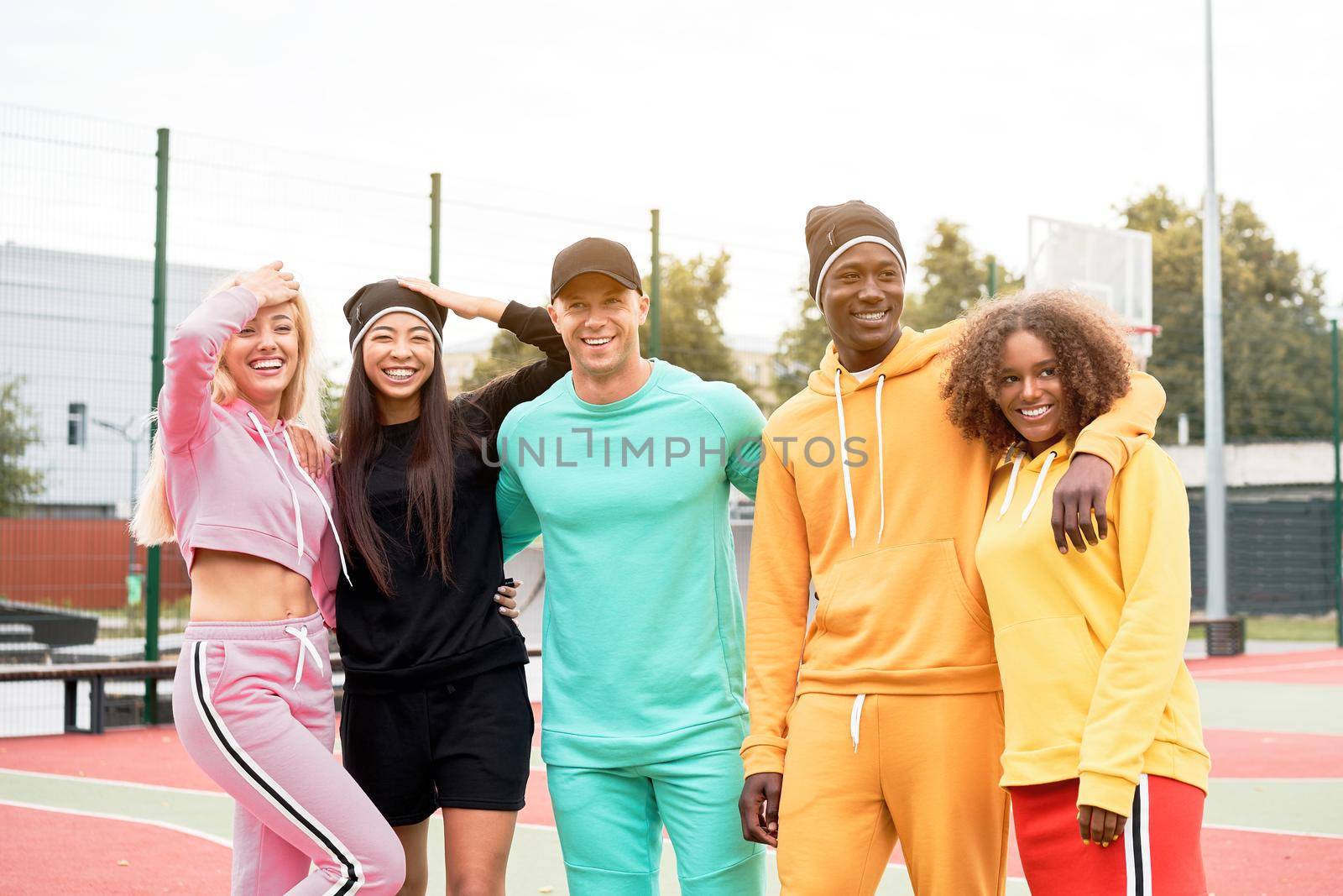 Multi-ethnic group teenage friends. African-american asian caucasian student spending time together Multiracial friendship Happy smiling People dressed colorful sportswear meeting outdoor sportground