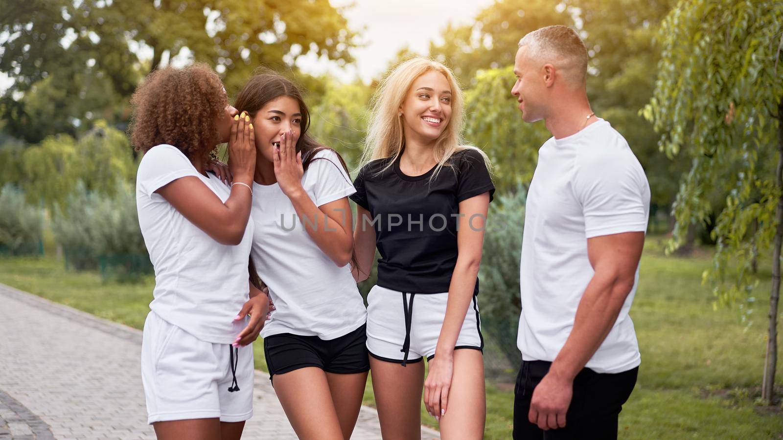 Multi-ethnic group teenage friends. African-american asian caucasian student spending time together Multiracial friendship Happy smiling People dressed black white sportswear meeting outdoor