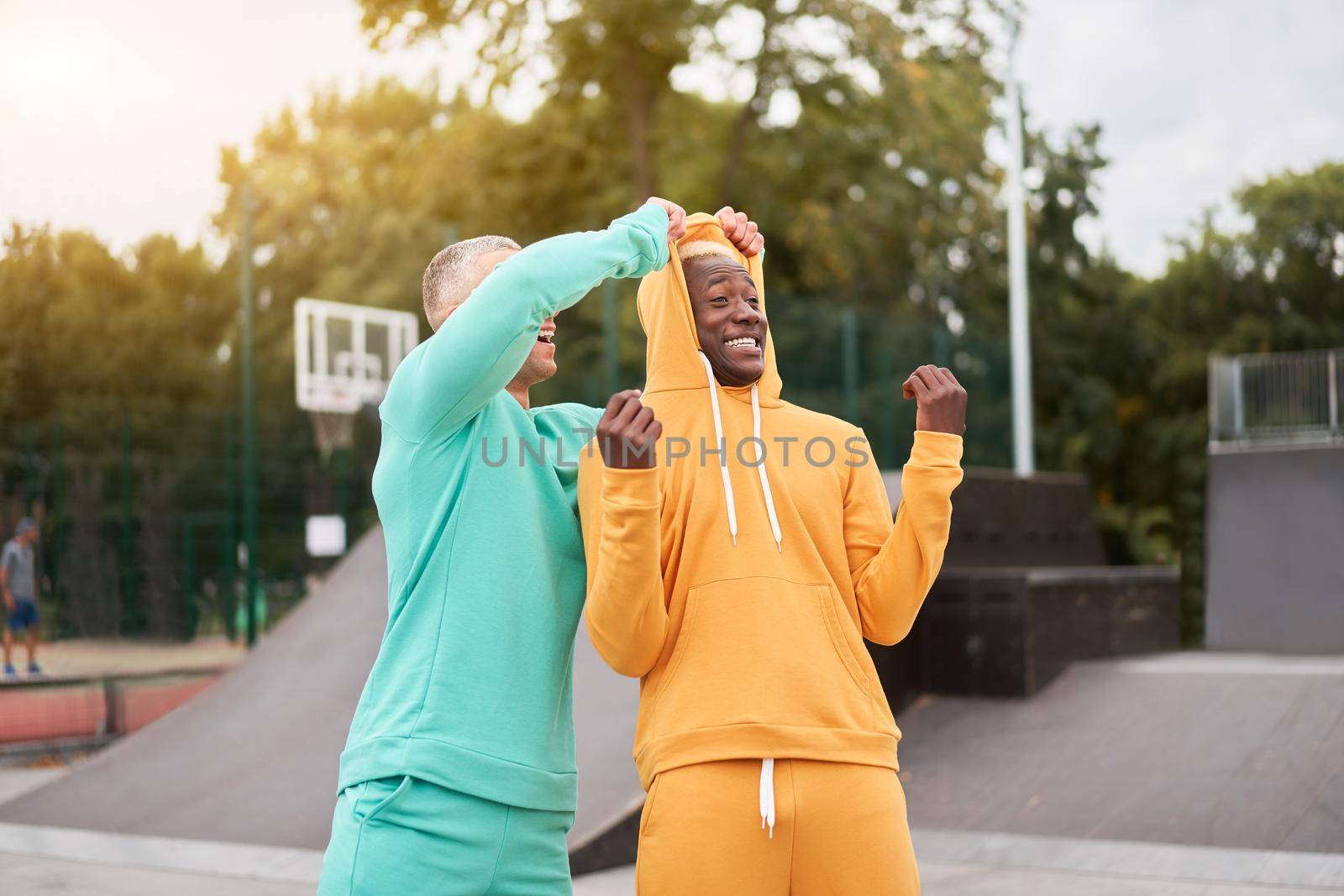 Multi-ethnic friendship Black african-american and caucasian guy friends spending time together on skate park by andreonegin