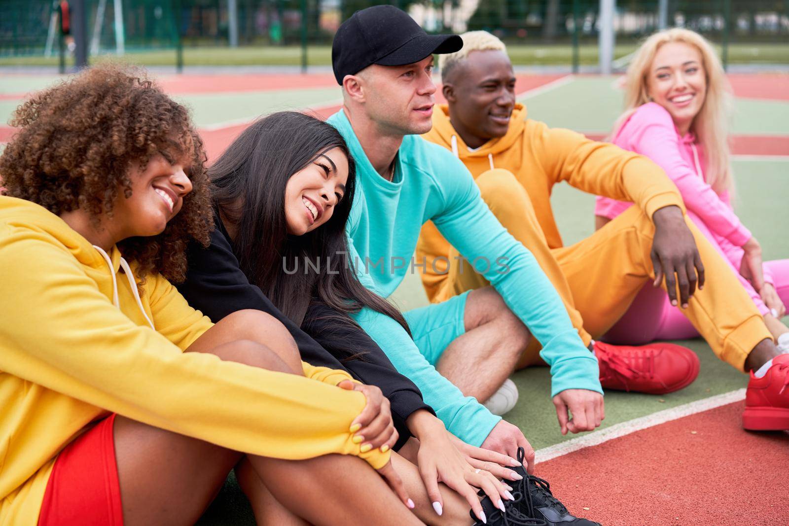 Multi-ethnic group teenage friends. African-american asian caucasian student spending time together Multiracial friendship Happy smiling People dressed colorful sportswear meeting outdoor sportground