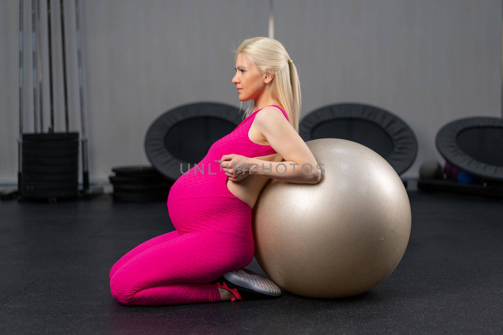 Pregnant woman exercise with fitness bal in gym by andreonegin