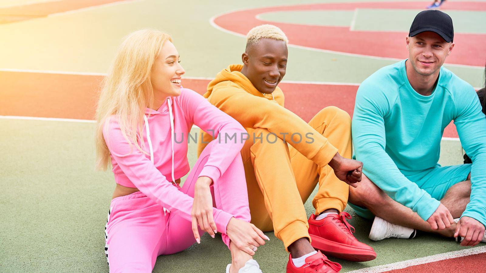 Multi-ethnic group teenage friends. African-american caucasian student spending time together Multiracial friendship Happy smiling People dressed colorful sportswear meeting outdoor sportground