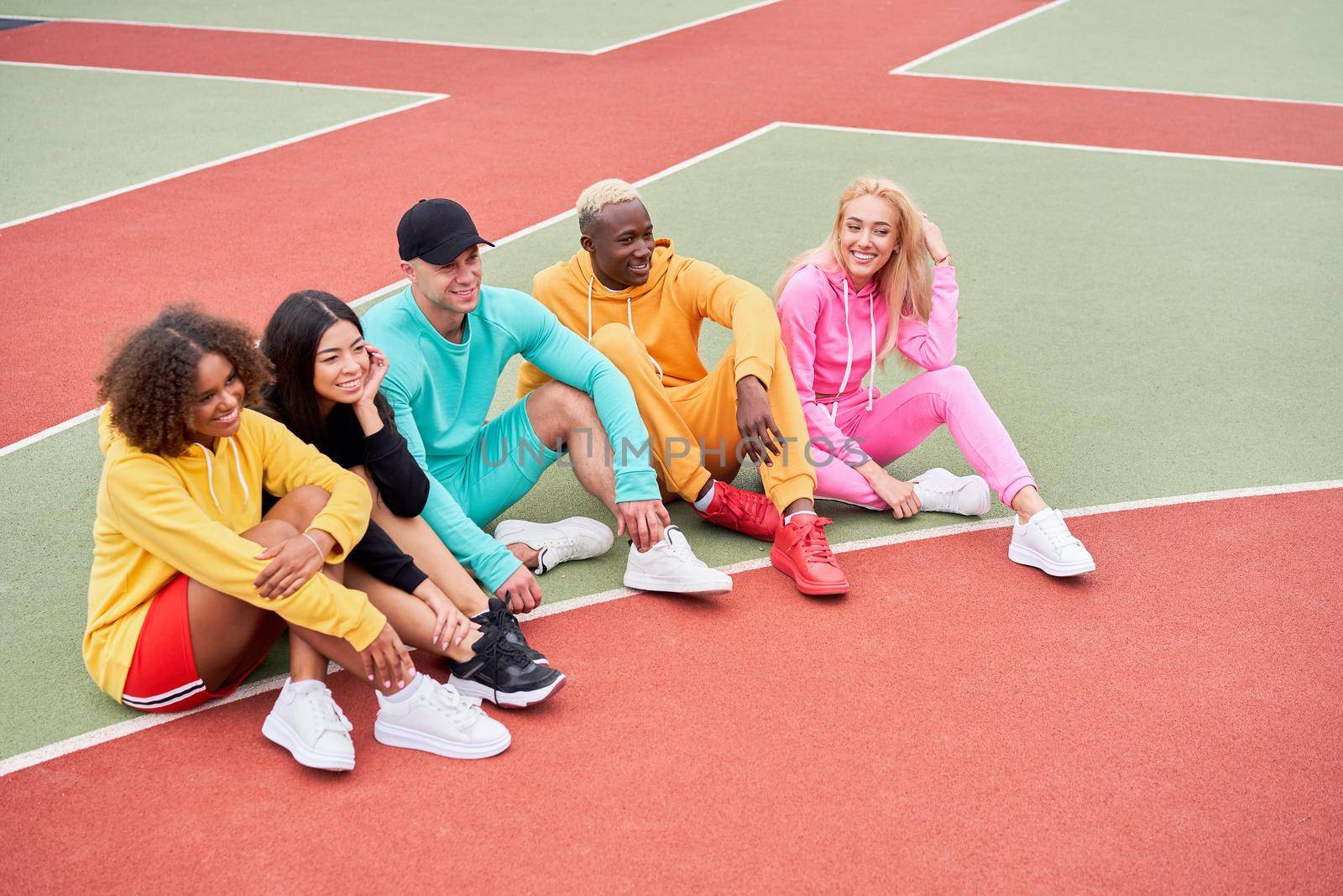 Multi-ethnic group teenage friends. African-american asian caucasian student spending time together Multiracial friendship Happy smiling People dressed colorful sportswear meeting outdoor sportground